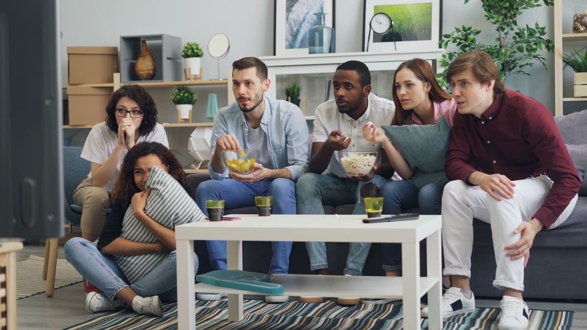 Sekelompok orang-orang duduk di sofa menonton TV