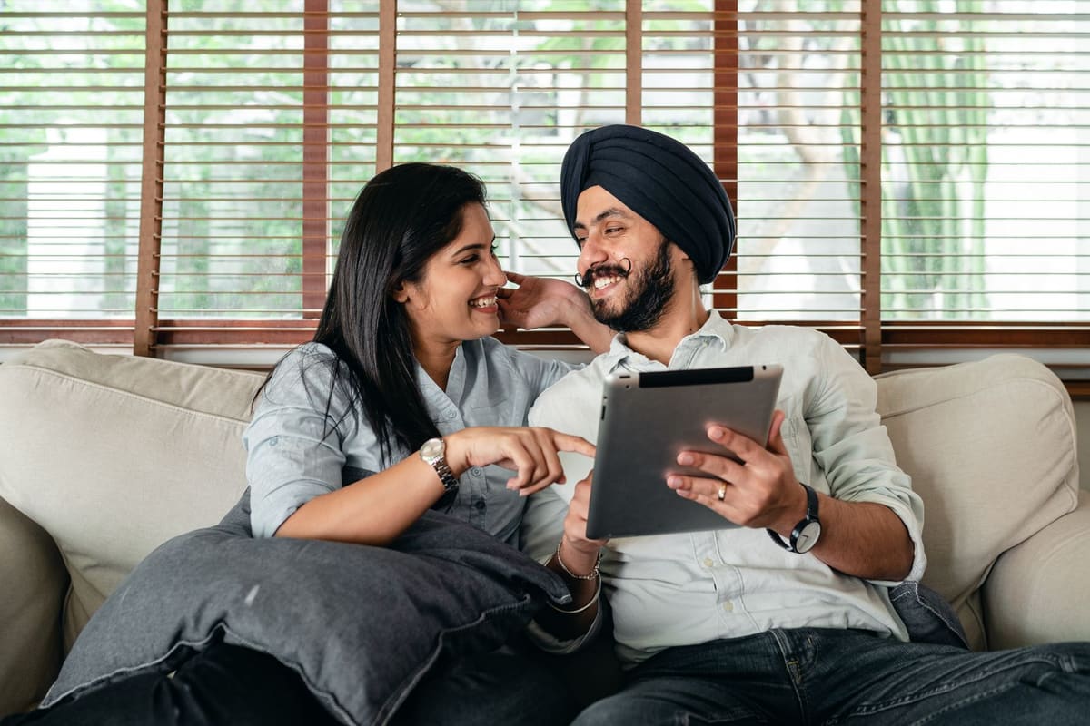 Pasangan berbaring di kasur menonton netflix di laptop