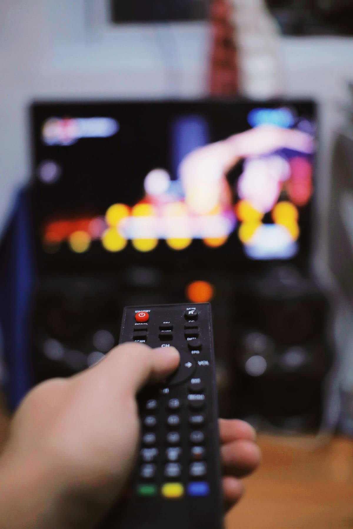 Seseorang memegang remote control di depan televisi WIhjjmqk5II