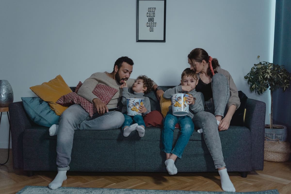 Pria duduk di sofa memegang remote control