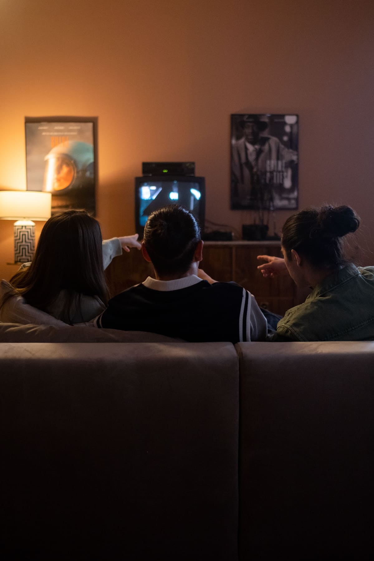 Teman-teman menonton TV di sofa dan pointing something di TV player