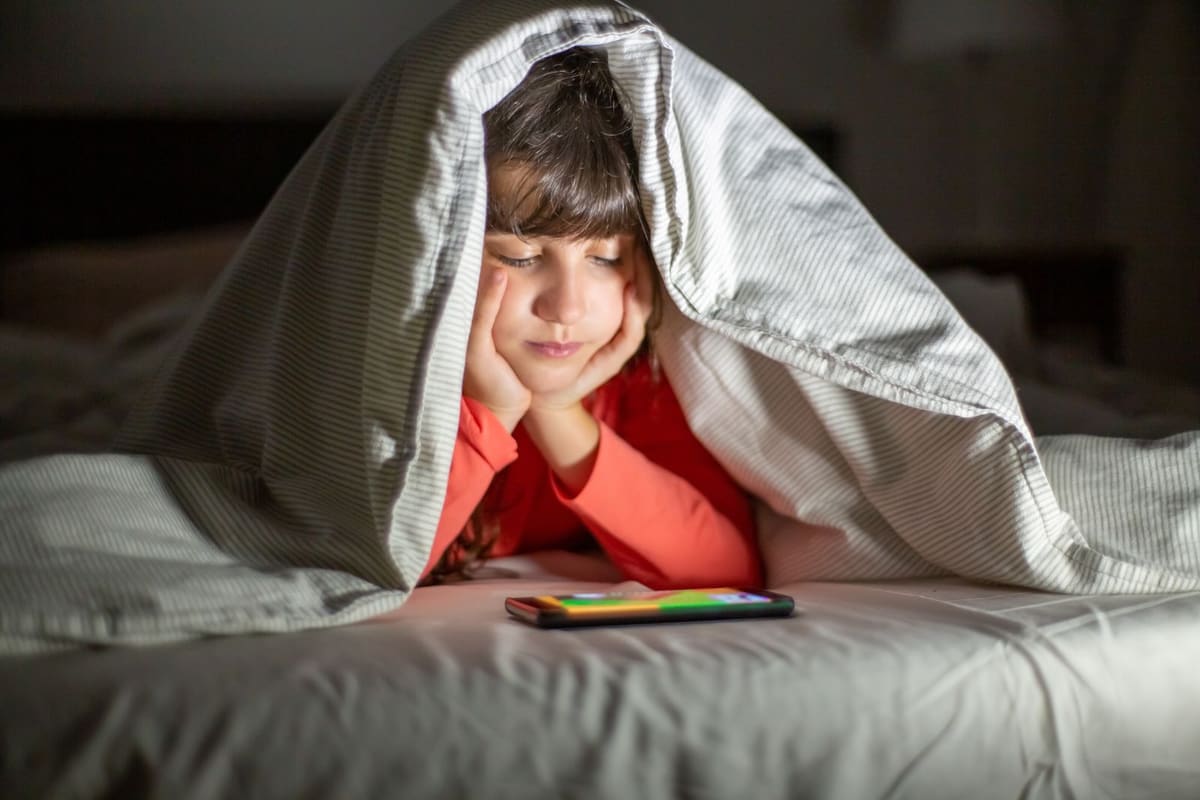 Foto anak perempuan di red shirt menonton di ponsel