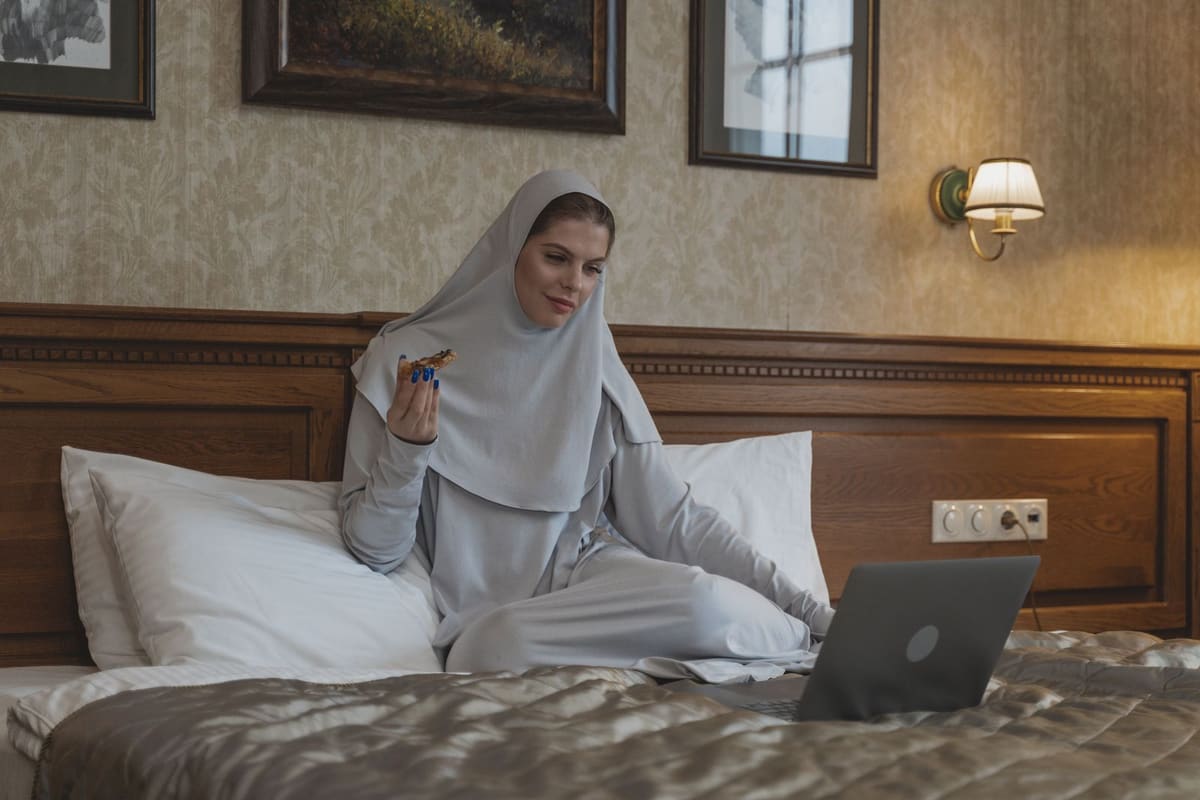 Wanita eating pizza sambil menonton di laptop