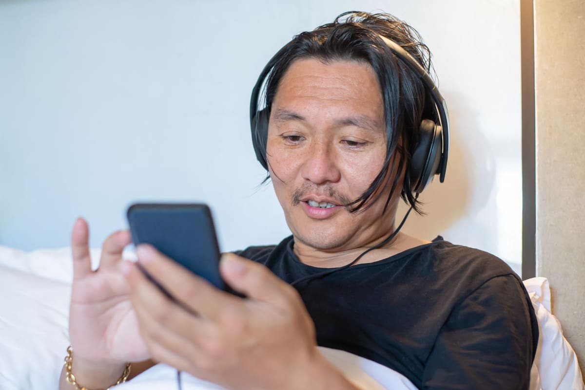 Pria wearing headphone dan memakai ponsel