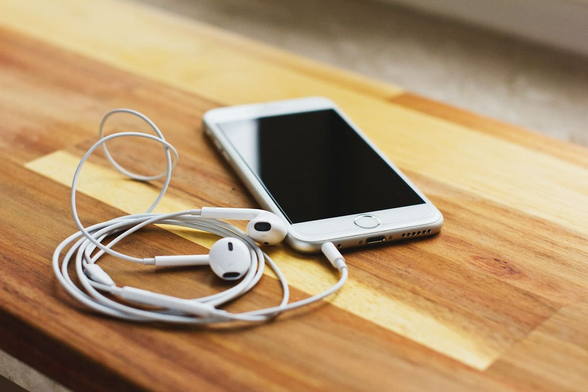 Silver iphone 6 dengan earpods di wooden meja