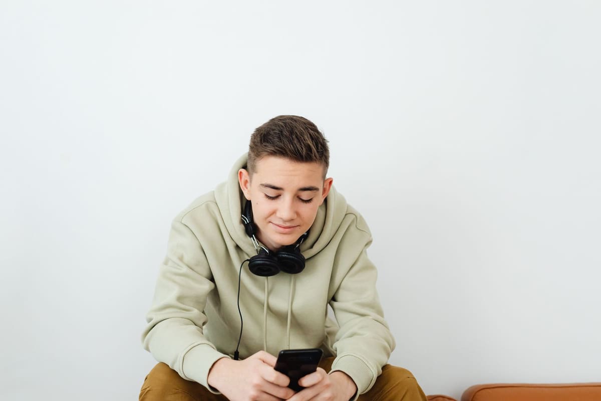 Pria dengan headphone around neck memakai cell ponsel